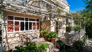 A building with a balcony, potted plants, and outdoor seating. - Apartments Klis -Two-Bedroom Apartment with Terrace (Soline)