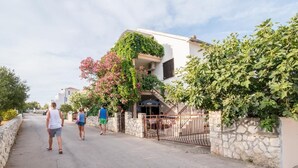 A residential street with a house featuring a stone wall and a metal gate. - Apartments Fidelis - Two Bedroom Apartment with Terrace and Garden View (Okrug Gornji)