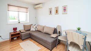 A modern living room with a sofa, a small table, a chair, and a window with blinds.