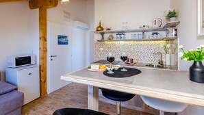Ett kompakt kök med en matplats, utrustat med mikrovågsugn, ett litet kylskåp, en diskho och ett matbord med stolar.