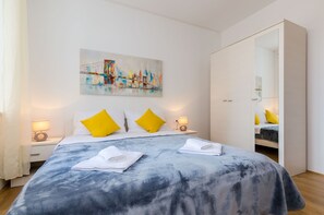 Quarto de hotel moderno com uma cama grande, duas mesas de cabeceira com abajures, um quadro na parede e um guarda-roupa com espelho.