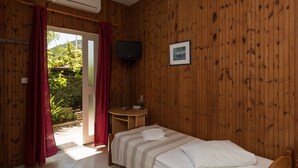 Een kamer met houten lambrisering, een bed, een televisie en een kleine tafel.
