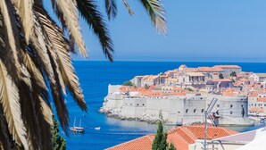A coastal city with historic architecture, a fortified wall, and a clear blue sea.