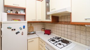 A kitchen with a white refrigerator, a red toaster, and a gas stove.