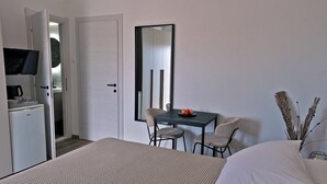 A hotel room with a bed, a desk with two chairs, a television, and a small kitchenette. - Villa Katarina - Comfort Double Room with Terrace (Ground Floor) (Dubrovnik)