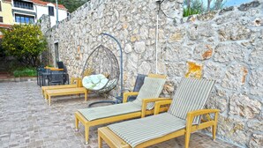 A patio area with wicker furniture, including two lounge chairs and a table, set against a stone wall. - Villa Katarina - Comfort Double Room with Terrace (Ground Floor) (Dubrovnik)