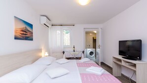 Une chambre à coucher avec un lit, une télévision, un lave-linge et un tableau accroché au mur.