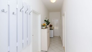 Un couloir aux murs blancs, doté d’un sol carrelé et d’une porte au fond.