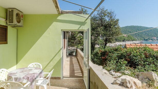 Un balcon avec vue sur la mer, une table avec des chaises et un appareil de climatisation.