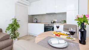 Uma cozinha moderna com armários brancos, forno embutido e área de jantar com mesa posta para dois.