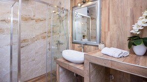 Ein modernes Badezimmer mit einer Duschkabine aus Glas, einem weißen Waschbecken und einem Holzbadezimmerunterschrank.