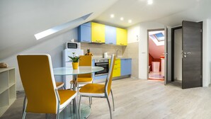 Una cocina moderna con armarios amarillos y azules, una mesa de comedor de cristal y sillas naranjas.