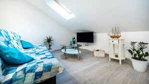 Una habitación moderna y luminosa con cama, una mesita redonda, televisor y una planta en maceta.
