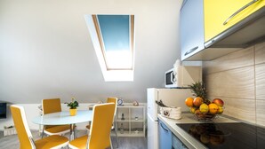 Una cocina moderna con comedor, que cuenta con un tragaluz, un frutero y un microondas.