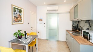 A modern kitchen with a dining area, featuring a table with chairs, a microwave, and a sink. - Apartment Villa Palma- Studio Apartment with Balcony and Sea View (Mlini)