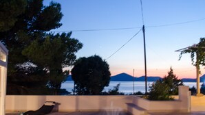 Ein Steinfountain in einem Garten mit Blick auf das Meer und die Berge im Hintergrund.