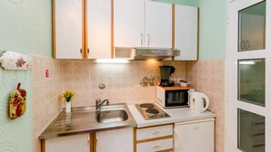 A compact kitchen with a sink, stove, microwave, and cabinets.
