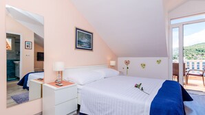 A bedroom with a bed, bedside tables, a mirror, and a view of the outside.