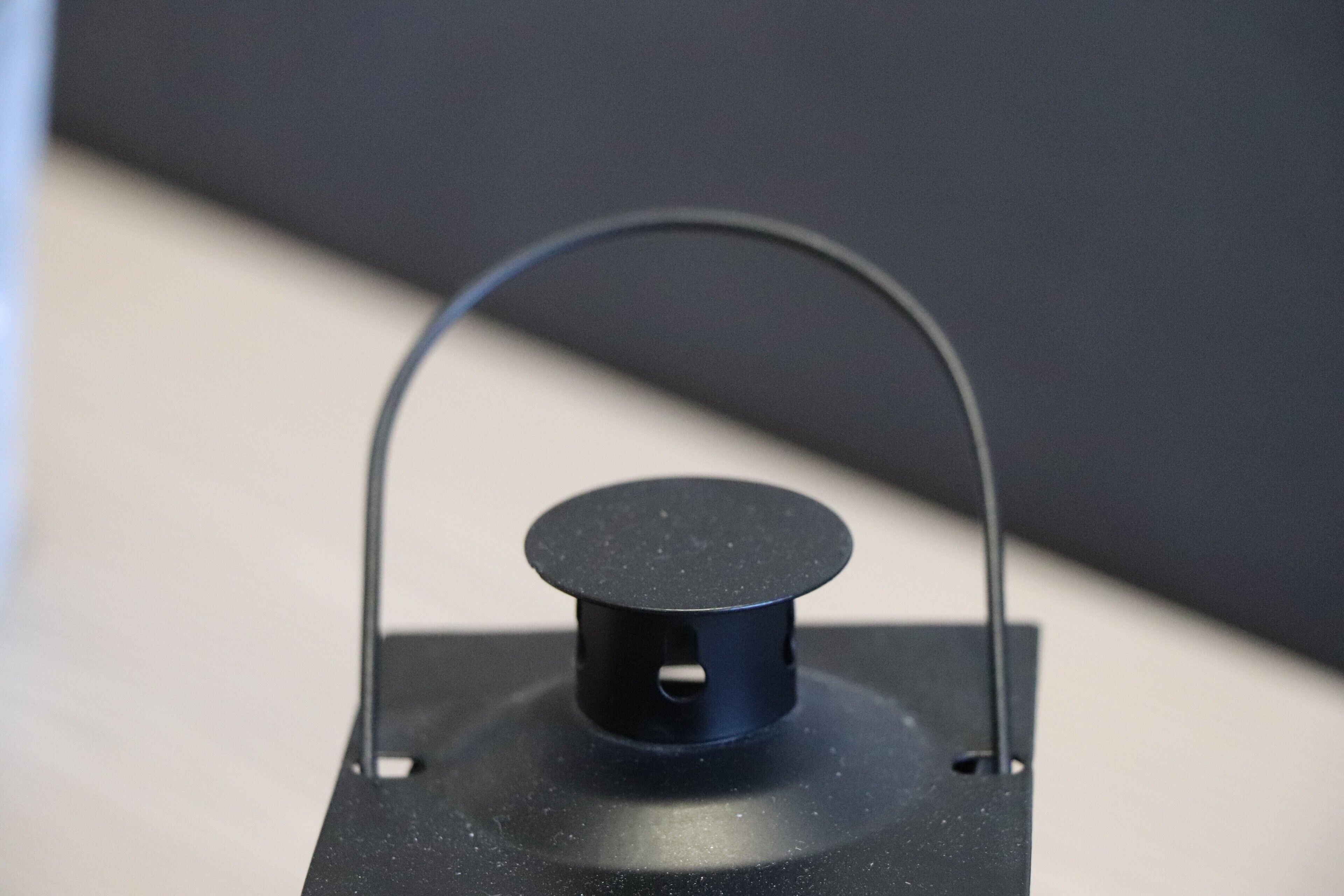 Een zwart, rond object met een handvat, op een vlak oppervlak geplaatst.