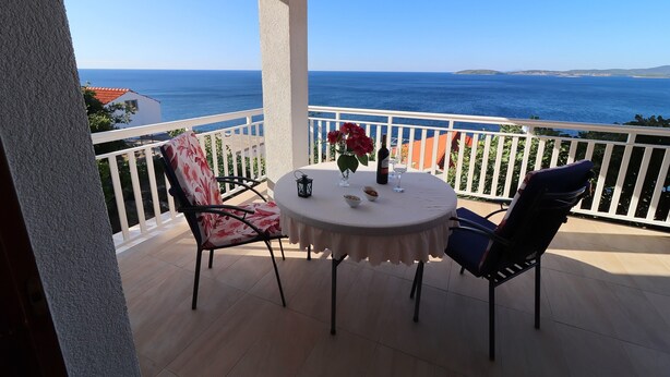 Ein Balkon mit Tisch, Stühlen und Meerblick.