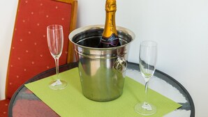 A champagne bottle in a metal bucket with two empty glasses on a table with a green placemat. - Apartments Versus- Studio Apartment with Terrace (Mlini)