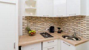 A modern kitchen with white cabinets, a wooden countertop, a gas stove, a sink, and a tiled backsplash. - Apartments Versus- Studio Apartment with Terrace (Mlini)