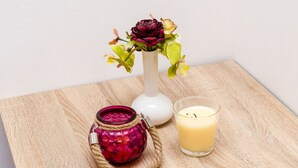 Una mesa de madera con un jarrón de flores, una vela y un vaso de leche.