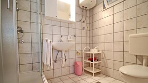 Een badkamer met een douche, wastafel en toilet.