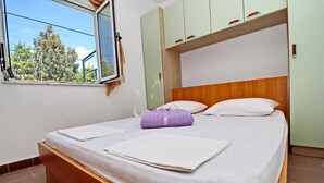Een slaapkamer met een bed, een raam en uitzicht op bomen.