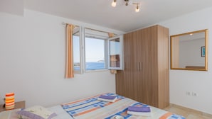 A bedroom with a bed, a window with curtains, a wardrobe, and a bedside table with a lamp and a cup. - Apartments Lovro - Duplex One Bedroom Apartment with Terrace and Partial Sea View (1) (Lozica)
