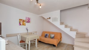 A compact living space with a dining area, a sofa, and a staircase. - Apartments Lovro - Duplex One Bedroom Apartment with Terrace and Partial Sea View (1) (Lozica)