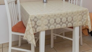 A dining table with a lace tablecloth, white chairs, and a vase with lavender flowers. - Apartments Lovro - Duplex One Bedroom Apartment with Terrace and Partial Sea View (1) (Lozica)