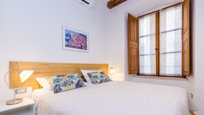 A neatly made bed with a wooden headboard, a bedside lamp, and a framed picture on the wall.