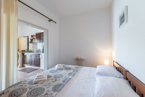 Ein Schlafzimmer mit Bett, Nachttisch und Blick auf einen Küchenbereich.