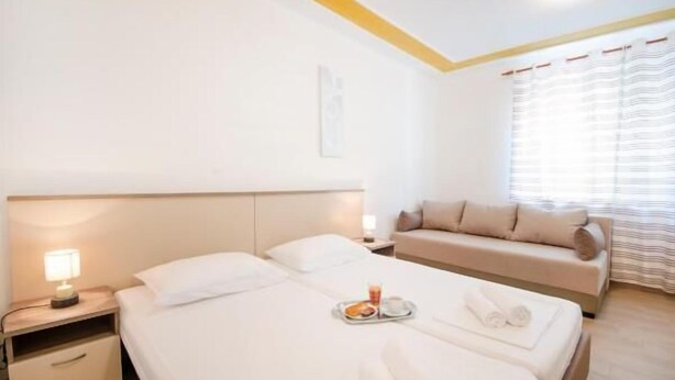 Une chambre d’hôtel avec un lit, une table de chevet, un canapé et une fenêtre avec des rideaux.