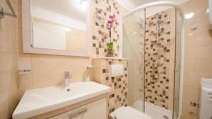 Une salle de bain avec un lavabo, des toilettes et une douche.