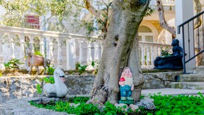 Un jardin agrémenté d’une statue de cygne, d’un arbre et d’une statue d’un homme tenant une pomme rouge.