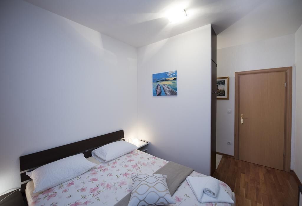 Une chambre à coucher avec un lit, une table de chevet, un tableau au mur et une porte en bois.