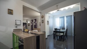 Een moderne keuken met een houten aanrecht, groene kastjes, en een eethoek met tafel en stoelen.