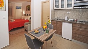 Ein kleines Hotelzimmer mit einer Küchenzeile, einem Essbereich und einem Bett.