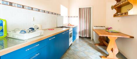 A kitchen with blue cabinets, a wooden table, and a tiled floor.