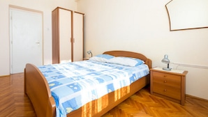 Un dormitorio con cama de madera, mesita de noche, lámpara y armario.