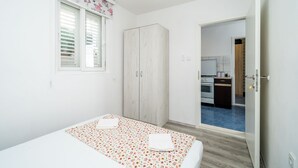 A bedroom with a bed, a wardrobe, and a view into the kitchen.