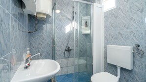 A bathroom with a glass-enclosed shower, a white sink, and a toilet.