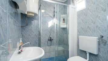 A bathroom with a glass-enclosed shower, a white sink, and a toilet.