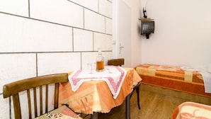 A small room with a wooden table and a bed, both covered with patterned tablecloths. - Katarina rooms - twin room (Dubrovnik)