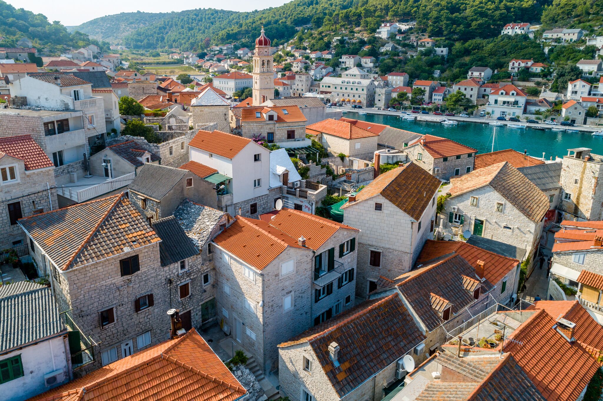 A coastal town with historic stone buildings, a prominent tower, and a marina.