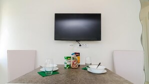 Una mesa de comedor con un televisor de pantalla plana montado encima, dos sillas y una caja de cereales.