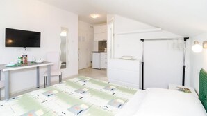 Habitación de hotel con cama, escritorio, televisor y kitchenette.