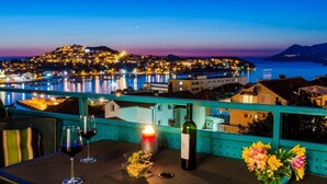 Eine Terrasse mit Tisch für zwei Personen, einer Weinflasche und einer Kerze.